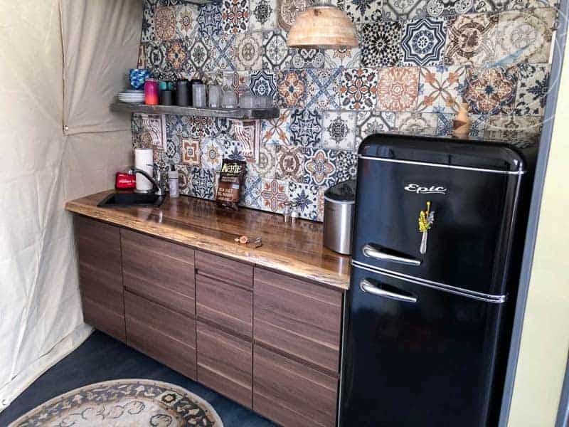 Retro kitchen with patterned tile backsplash, black vintage-style refrigerator, wooden countertop, coffee essentials, and cozy decor, perfect for Atlantic Destinations travel accommodations.