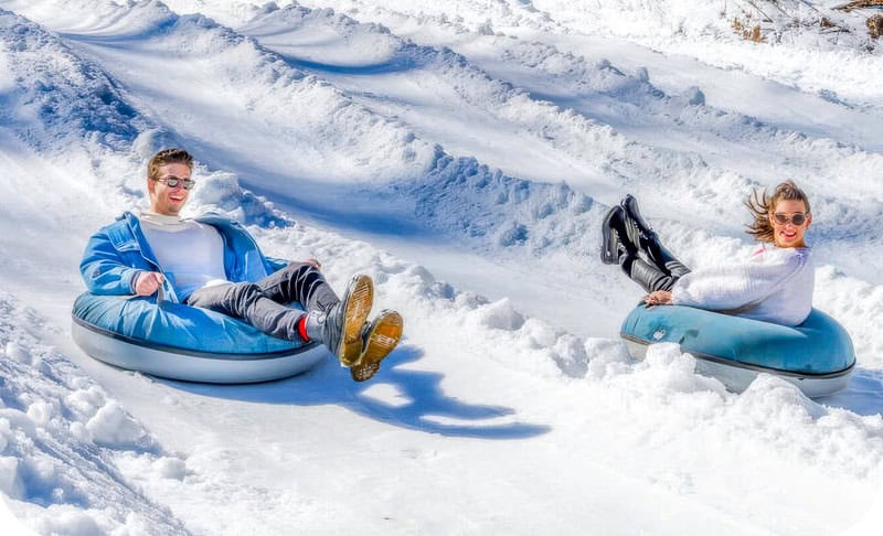 Things to do in North Carolina in winter - a couple enjoying snow tubing at Tube World at Cataloochee.